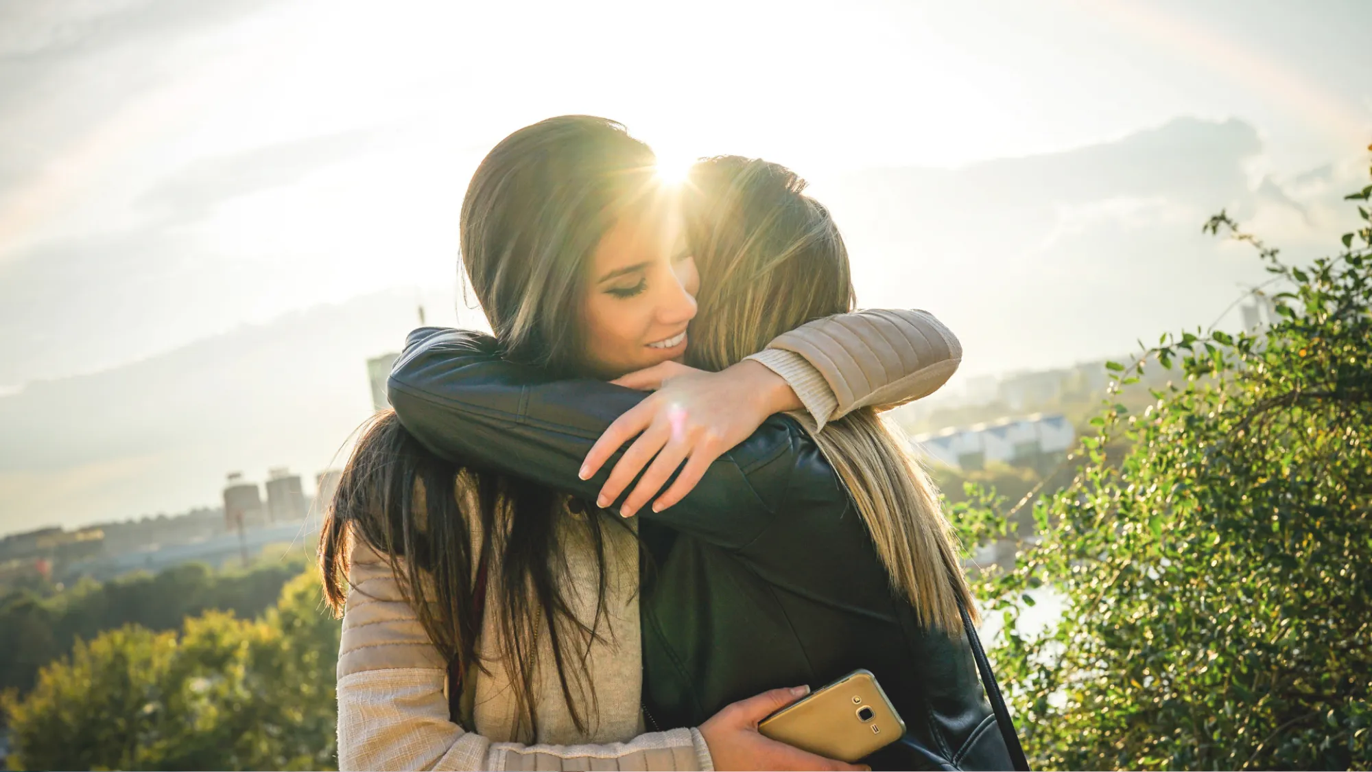 Two friends holding each other close at golden hour